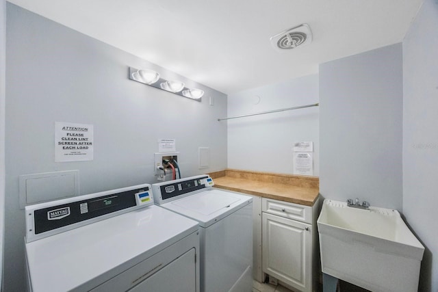 laundry area featuring cabinet space, visible vents, separate washer and dryer, and a sink