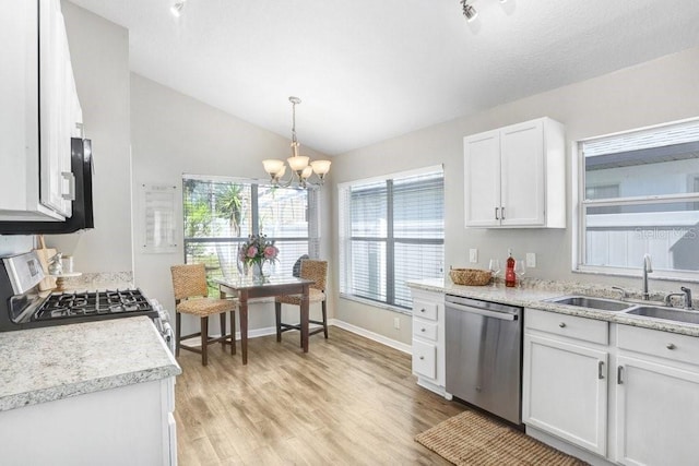 kitchen with appliances with stainless steel finishes, white cabinets, lofted ceiling, pendant lighting, and sink