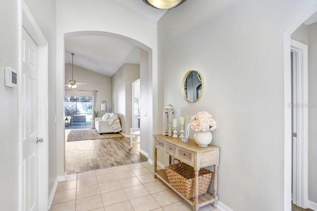 corridor with light tile patterned flooring and vaulted ceiling