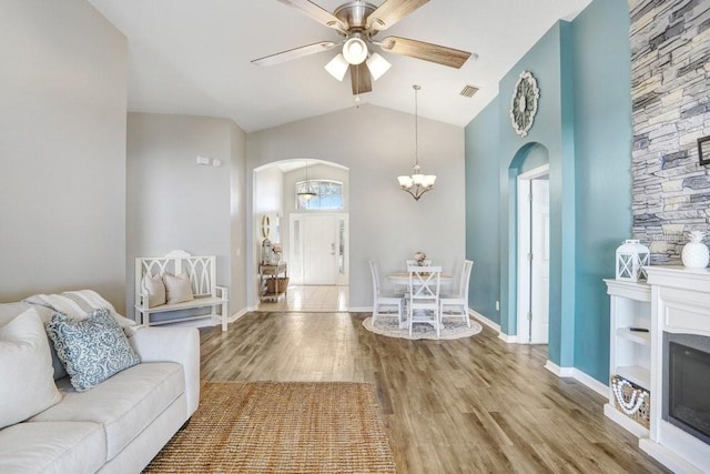 living room with vaulted ceiling, hardwood / wood-style floors, and ceiling fan with notable chandelier