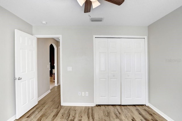 unfurnished bedroom featuring ceiling fan, light hardwood / wood-style floors, and a closet