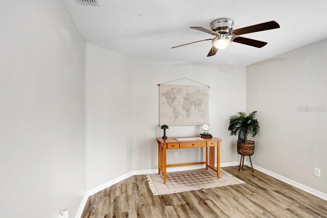 interior space with a textured ceiling, hardwood / wood-style flooring, and ceiling fan