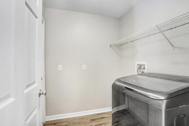 laundry area featuring hardwood / wood-style floors, washer / dryer, and a textured ceiling