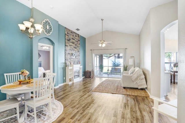 dining space with ceiling fan with notable chandelier, wood finished floors, arched walkways, and baseboards