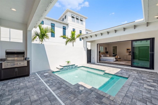 view of pool with grilling area, a patio area, and pool water feature