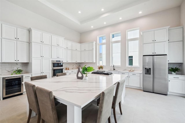 kitchen featuring white cabinetry, stainless steel appliances, beverage cooler, and a kitchen island