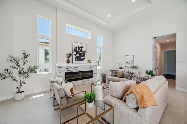 tiled living room featuring a towering ceiling, a tray ceiling, and a tiled fireplace