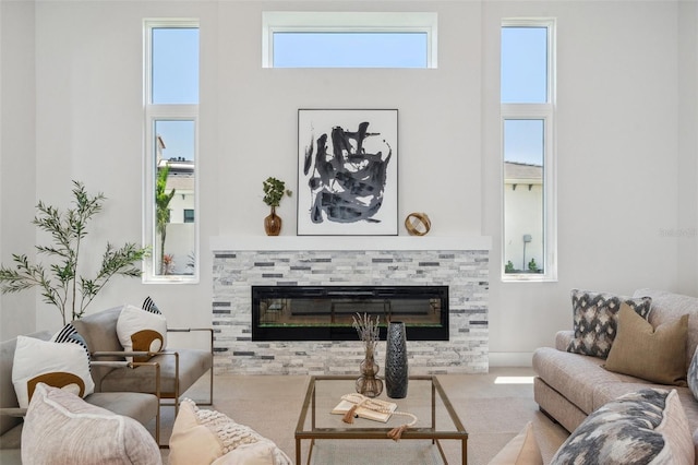 carpeted living room featuring a tiled fireplace and a towering ceiling