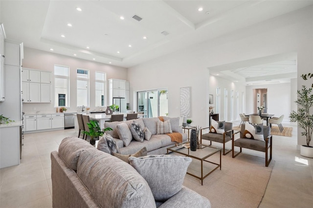 living room with a tray ceiling, a high ceiling, and light tile patterned floors