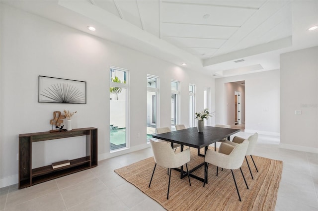 dining room with a tray ceiling and light tile patterned flooring