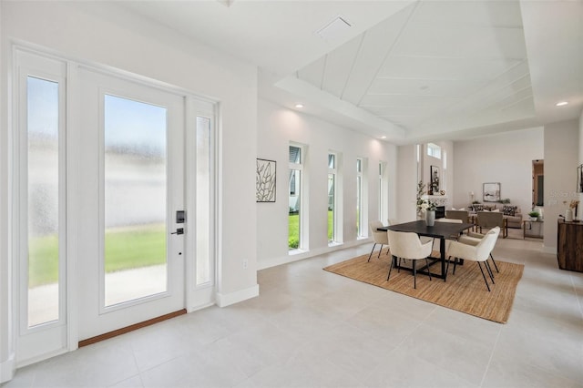 dining space featuring a raised ceiling and light tile patterned floors