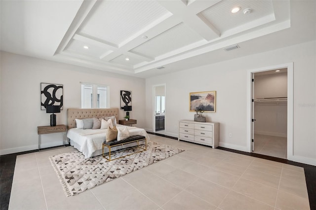 tiled bedroom with a walk in closet, coffered ceiling, and beam ceiling