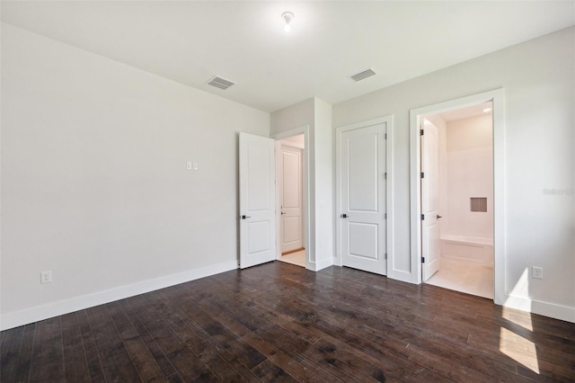 unfurnished bedroom featuring dark wood-type flooring and ensuite bathroom