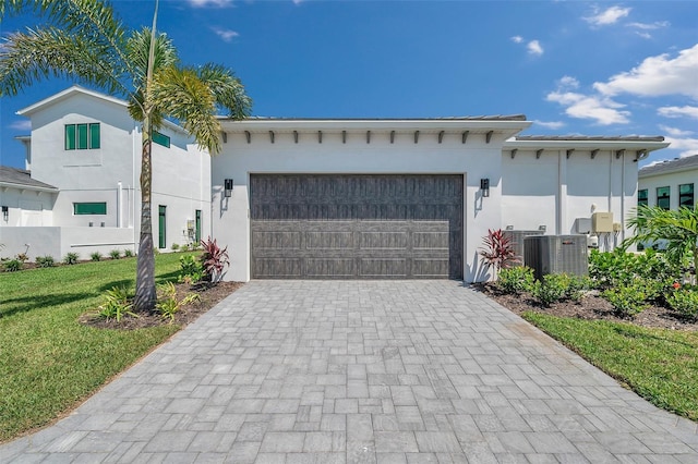 view of front of home featuring cooling unit, a garage, and a front yard