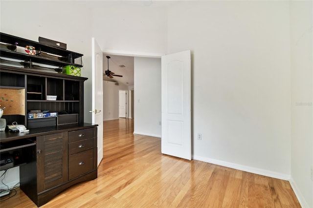 office area featuring light wood-type flooring, ceiling fan, and a high ceiling