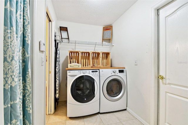 laundry room featuring washing machine and dryer, a textured ceiling, and light tile patterned flooring