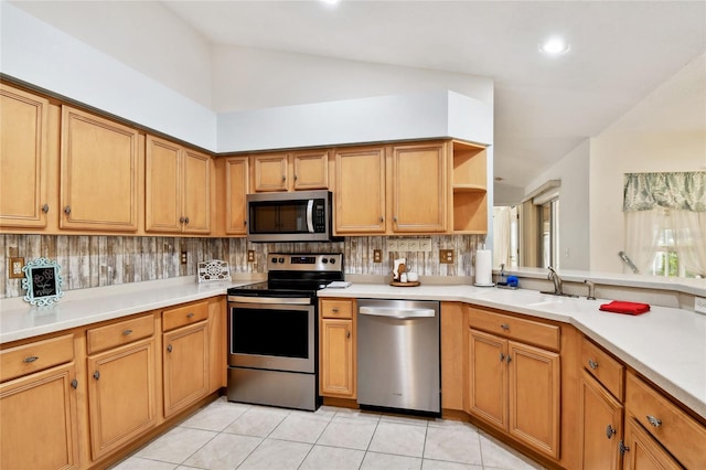 kitchen with sink, vaulted ceiling, tasteful backsplash, light tile patterned floors, and appliances with stainless steel finishes