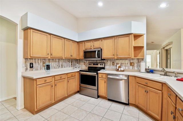 kitchen featuring sink, vaulted ceiling, tasteful backsplash, appliances with stainless steel finishes, and light tile patterned flooring