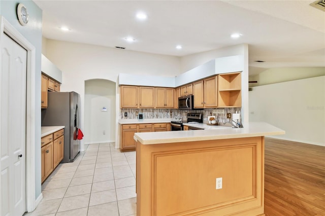 kitchen featuring decorative backsplash, stainless steel appliances, vaulted ceiling, and kitchen peninsula