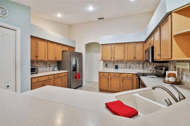 kitchen featuring lofted ceiling, stainless steel appliances, sink, tasteful backsplash, and light tile patterned flooring