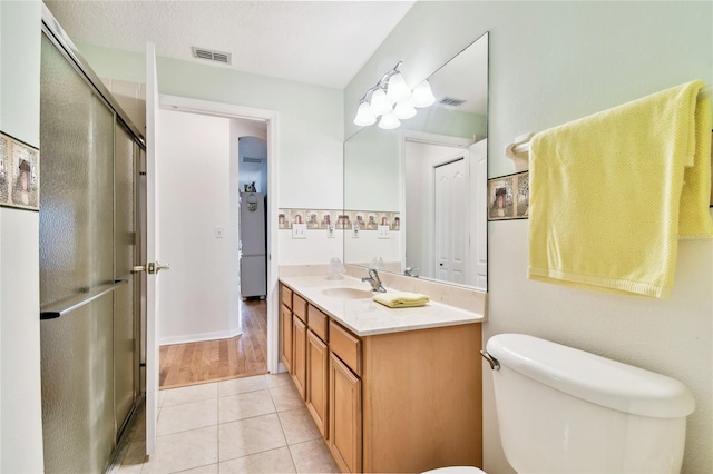 bathroom with vanity, toilet, a shower with shower door, and tile patterned floors