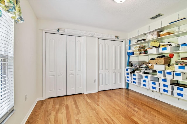 bedroom with multiple closets, a textured ceiling, and hardwood / wood-style floors