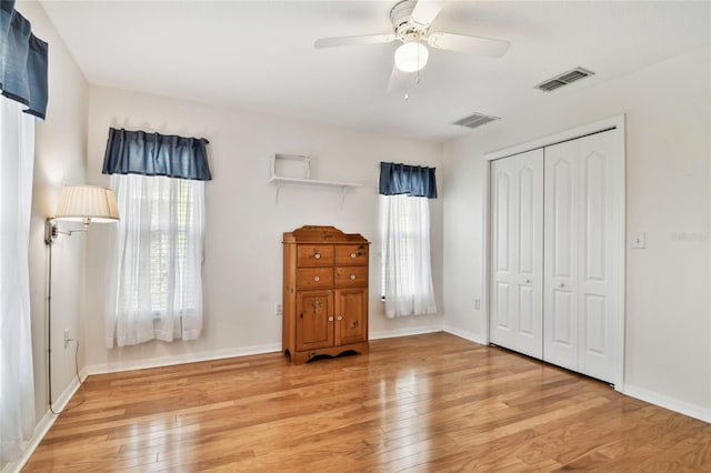 unfurnished bedroom with ceiling fan, light wood-type flooring, and a closet