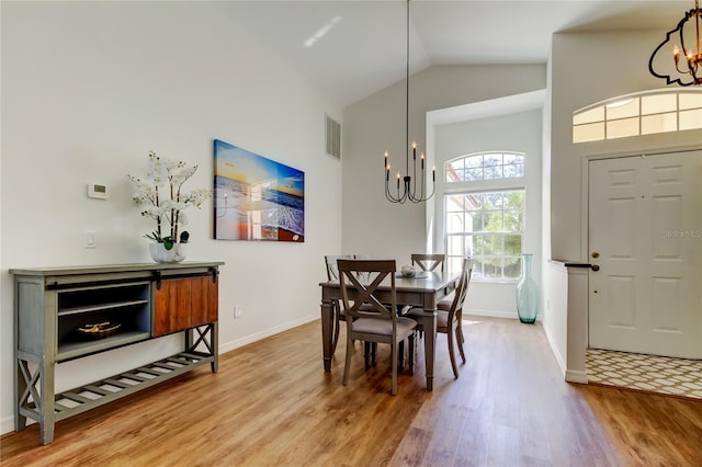 dining area with hardwood / wood-style flooring, high vaulted ceiling, and an inviting chandelier