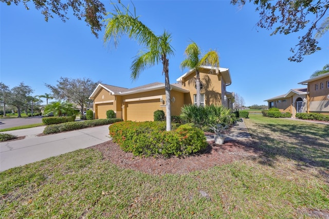 view of front of home with driveway, a front yard, an attached garage, and stucco siding