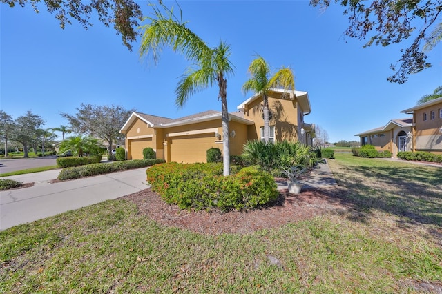 view of front of home with driveway, a front yard, an attached garage, and stucco siding