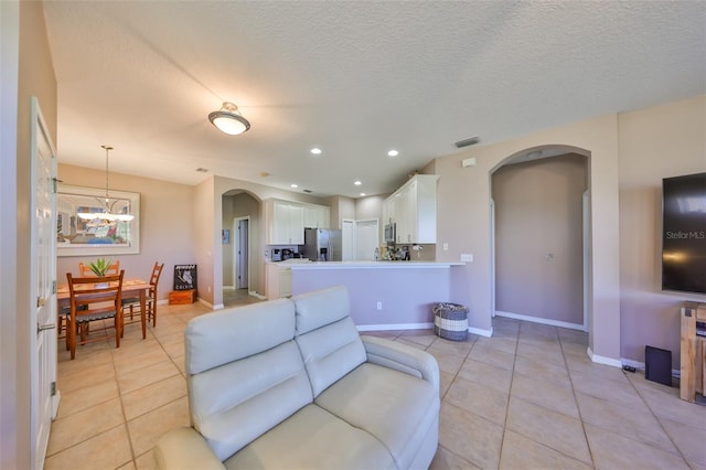 living room with arched walkways, light tile patterned floors, visible vents, and baseboards