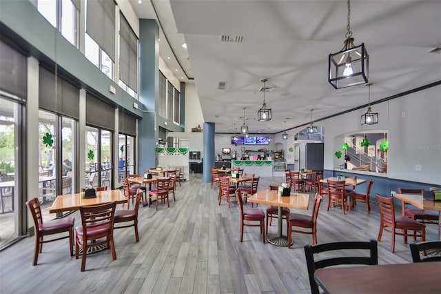 dining room with visible vents, light wood-type flooring, a towering ceiling, and recessed lighting