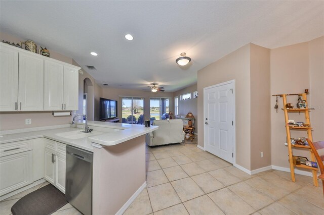kitchen with open floor plan, a peninsula, stainless steel dishwasher, white cabinetry, and a sink
