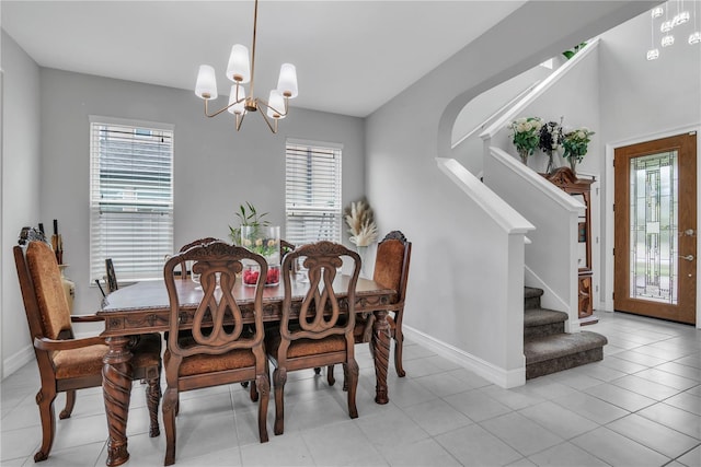 dining space with light tile patterned floors, baseboards, stairway, and a chandelier