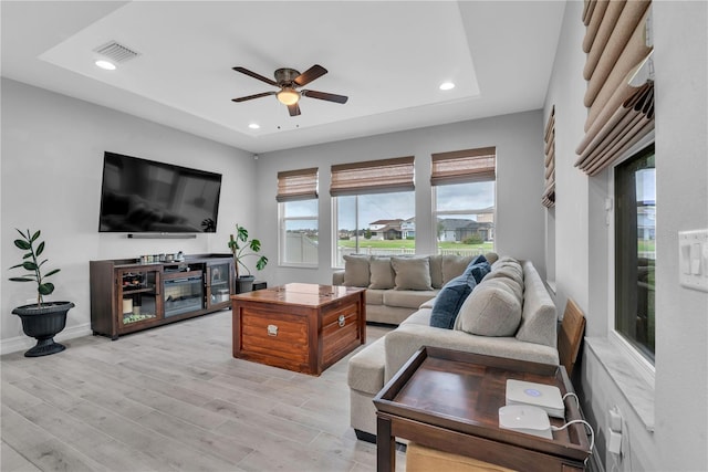 living area with visible vents, a raised ceiling, ceiling fan, light wood-style flooring, and recessed lighting