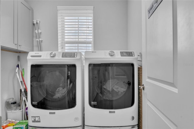 clothes washing area featuring washing machine and clothes dryer and cabinet space