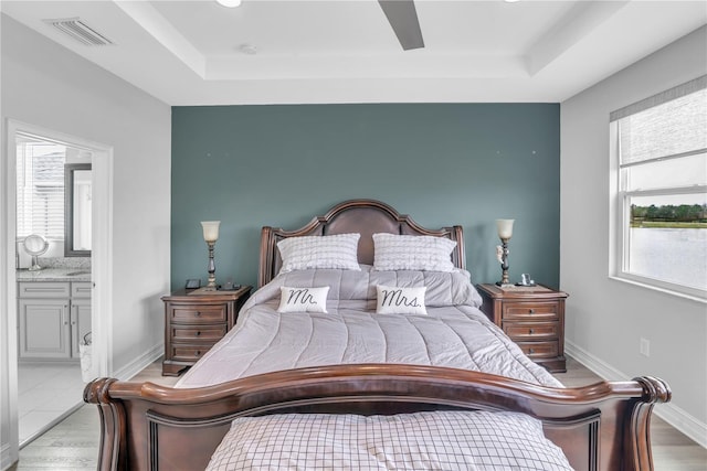 bedroom with multiple windows, visible vents, and a raised ceiling