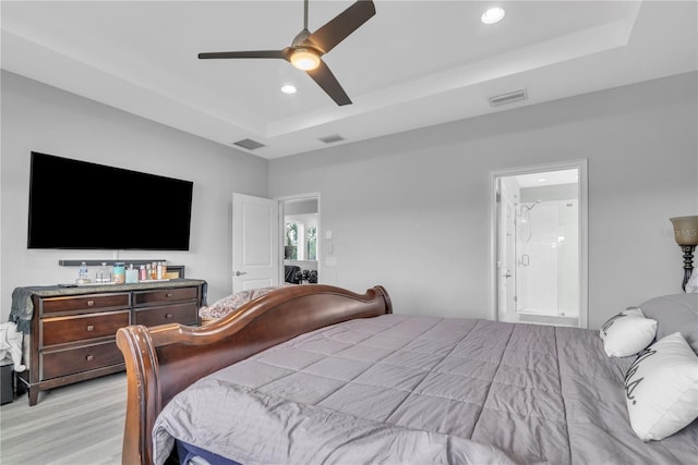 bedroom with light wood finished floors, a raised ceiling, visible vents, and recessed lighting