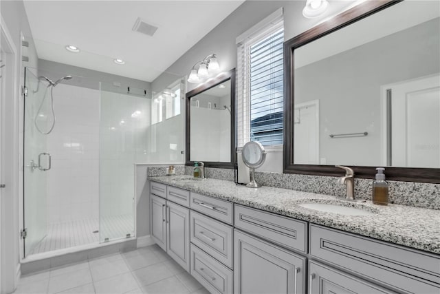 bathroom featuring double vanity, a stall shower, a sink, and visible vents