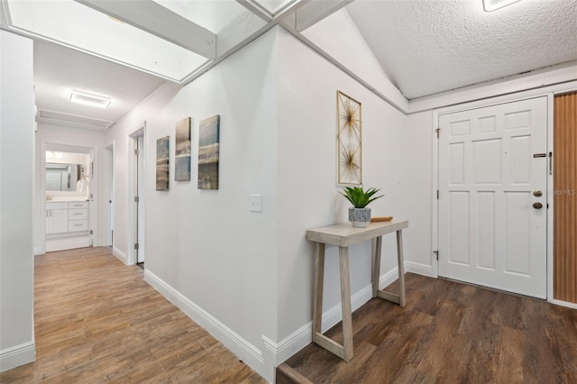 entrance foyer with baseboards, a textured ceiling, and wood finished floors