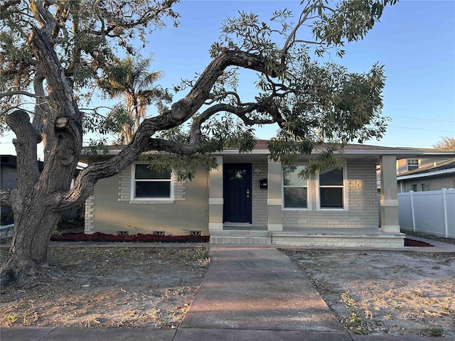 view of front of property with brick siding and fence