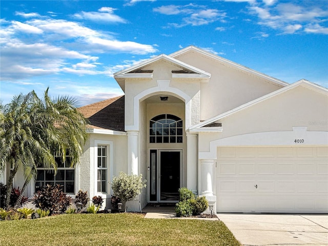 view of front facade featuring a garage, driveway, a front yard, and stucco siding