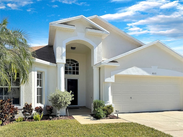 view of front of home with driveway, roof with shingles, an attached garage, and stucco siding