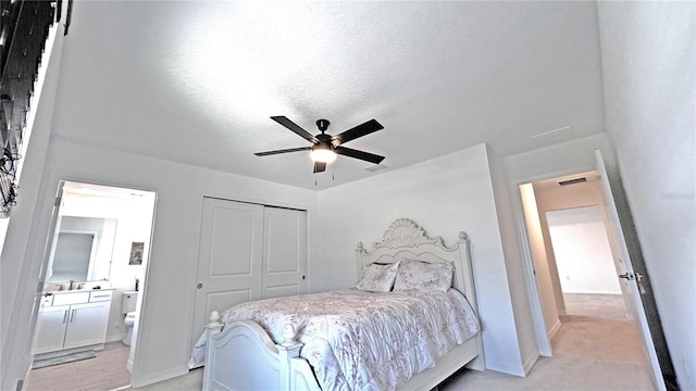 bedroom with a closet, visible vents, light carpet, connected bathroom, and a textured ceiling