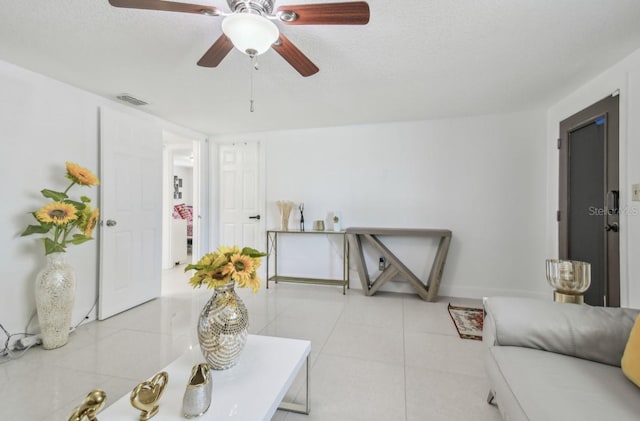 tiled living room featuring ceiling fan and a textured ceiling