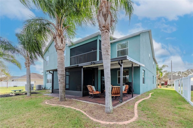 rear view of house featuring a lawn, a patio, a sunroom, and central AC