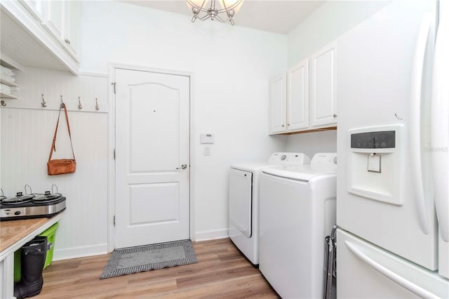 laundry area with washer and dryer, cabinets, and light hardwood / wood-style flooring
