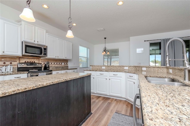 kitchen featuring hanging light fixtures, white cabinetry, stainless steel appliances, and sink
