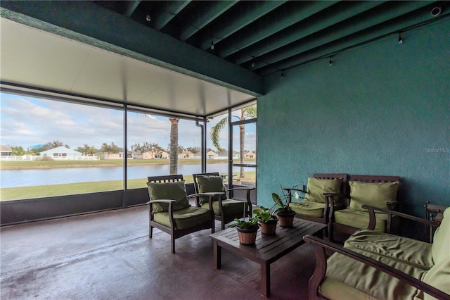 sunroom with beam ceiling, a water view, and a healthy amount of sunlight