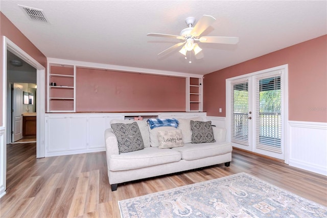 unfurnished living room featuring built in features, a textured ceiling, and light hardwood / wood-style floors